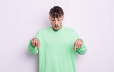 Genç yakışıklı adam şok olmuş, ağzı açık ve şaşkın, inançsızlık ve şaşkınlık içinde bakıyor ve onu işaret ediyor.