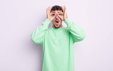 Genç yakışıklı adam şaşkın, şaşırmış ve şaşırmış hissediyor. Elinde şaşkın, inançsız bir bakışla gözlük tutuyor.