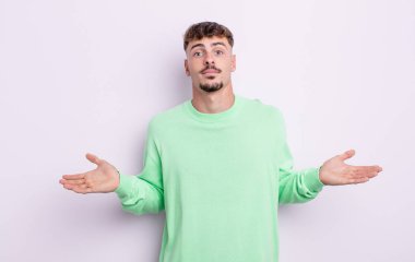 Genç yakışıklı adam şaşkın ve şaşkın hissediyor, doğru cevap veya karardan emin değil, bir seçim yapmaya çalışıyor.