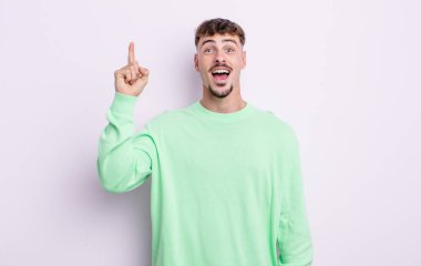 Genç yakışıklı bir adam bir fikri fark ettikten sonra mutlu ve heyecanlı bir dahi gibi hissediyor, neşeli bir şekilde parmağını kaldırıyor, eureka!