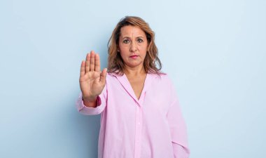 Orta yaşlı bir kadın ciddi, sert, hoşnutsuz ve kızgın görünüyor.