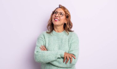 Orta yaşlı bir kadın mutlu, gururlu ve umutlu, merak ediyor ya da düşünüyor, çapraz kollarla fotokopi çekmeyi bekliyor.