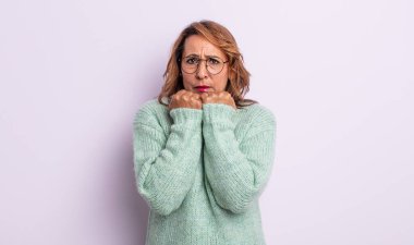 Orta yaşlı bir kadın endişeli, stresli ve korkmuş görünüyor, tırnaklarını yiyor ve yanal fotokopi için yer arıyor.