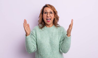 Orta yaşlı bir kadın mutlu, heyecanlı, şaşırmış ya da şaşırmış hissediyor, gülümsüyor ve hayret verici bir şeye şaşırıyor.