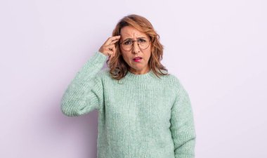 Orta yaşlı bir kadın kafası karışık ve şaşkın hissediyor. Deli, deli ya da aklını kaçırmış olduğunu gösteriyor.