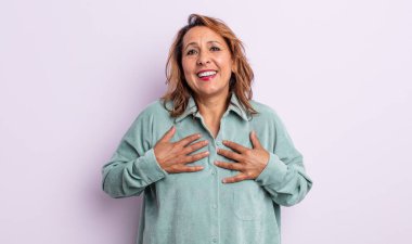 Orta yaşlı kadın mutlu, şaşırmış, gururlu ve heyecanlı görünüyor.