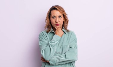 Orta yaşlı kadın ciddi görünüyor, kafası karışık, kararsız ve düşünceli, seçenekler ve seçenekler arasında şüpheci.