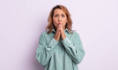 Orta yaşlı bir kadın endişeli, üzgün ve korkmuş hissediyor, elleriyle ağzını kapatıyor, endişeli ve berbat görünüyor.