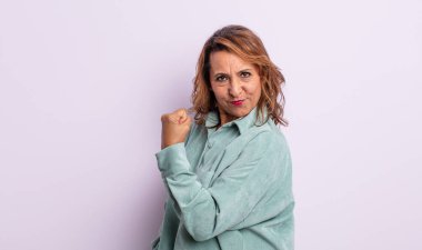 Orta yaşlı bir kadın kendini mutlu, tatmin olmuş ve güçlü hissediyor, kaslı ve formda, spor salonundan sonra güçlü görünüyor.