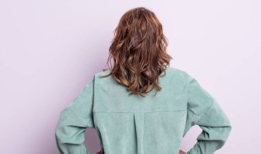 Orta yaşlı bir kadın kafası karışık ya da dolgun ya da şüphe ve soru dolu, merak ediyor, elleri kalçasında, dikiz aynasından.