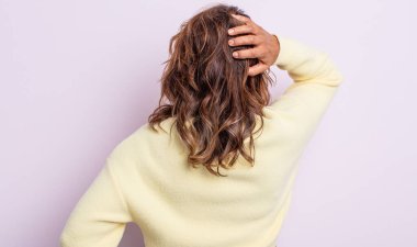 Orta yaşlı bir kadın bilgisiz ve kafası karışık, bir çözüm düşünüyor, eli kalçasında, diğeri kafasında, dikiz aynasından.