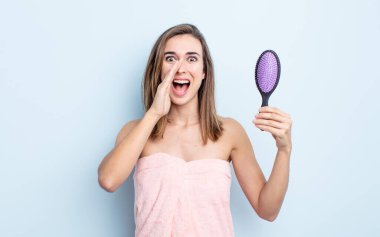 Genç, güzel bir kadın kendini mutlu hissediyor. Elleri ağzının kenarında bağırıyor. saç fırçası konsepti