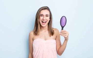 Genç ve güzel bir kadın mutlu ve hoş bir şekilde şaşırmış görünüyor. saç fırçası konsepti