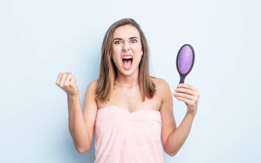 Genç ve güzel bir kadın sinirli bir ifadeyle agresif bir şekilde bağırıyor. saç fırçası konsepti