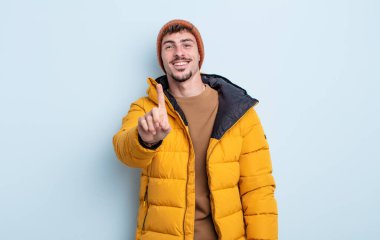 Genç yakışıklı adam gururla gülümsüyor ve kendinden emin bir numara oluyor. kış konsepti