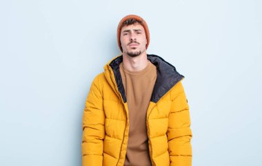 Genç ve yakışıklı bir adam üzgün ve mızmızlanıyor. Mutsuz bir bakışı var ve ağlıyor. kış konsepti