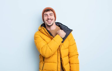 Genç yakışıklı adam kendini mutlu hissediyor ve bir meydan okumayla yüzleşiyor ya da kutluyor. kış konsepti