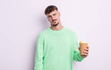 Genç yakışıklı adam şaşkın ve şaşkın hissediyor. kahve konseptini kaldır.