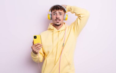 Genç ve yakışıklı bir adam stresli, endişeli ya da korkmuş hissediyor. Elleri başının üstünde. müzik konsepti