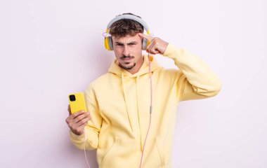 Genç yakışıklı adam kafası karışık ve şaşkın hissediyor, deli olduğunu gösteriyor. müzik konsepti