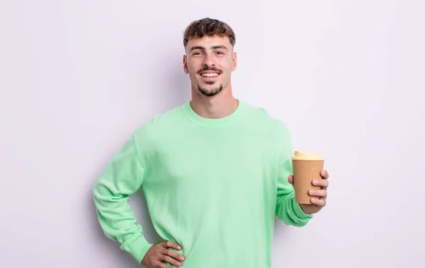 若いハンサムな男が喜んで笑顔で手を腰と自信を持って コーヒーの概念を取り上げ — ストック写真