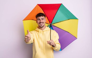 Genç ve yakışıklı bir adam gururlu, olumlu gülümsüyor. şemsiye kavramı