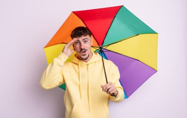 Genç yakışıklı adam mutlu, şaşkın ve şaşırmış görünüyor. şemsiye kavramı