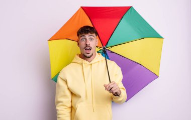 Genç ve yakışıklı bir adam çok şaşırmış ya da şaşkın görünüyor. şemsiye kavramı