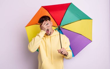 Genç, yakışıklı adam şok olmuş, korkmuş ya da korkmuş görünüyor. şemsiye kavramı