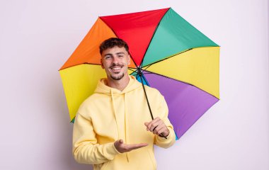 Genç yakışıklı adam neşeyle gülümsüyor, mutlu hissediyor ve bir konsept gösteriyor. şemsiye kavramı