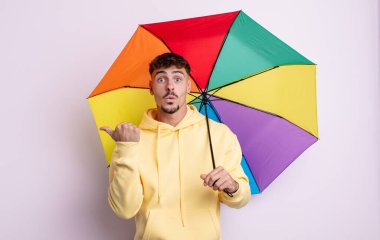 İnanamadığı için şaşırmış genç ve yakışıklı bir adam. şemsiye kavramı