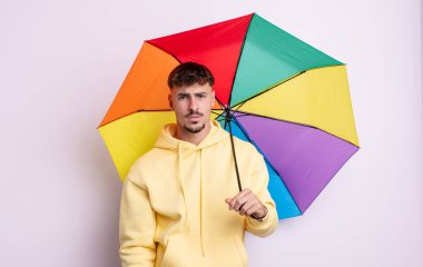 Genç ve yakışıklı bir adam üzgün ve mızmızlanıyor. Mutsuz bir bakışı var ve ağlıyor. şemsiye kavramı