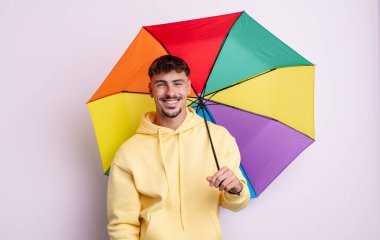 Genç yakışıklı adam mutlu ve hoş bir şekilde şaşırmış görünüyor. şemsiye kavramı