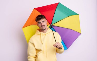 Genç yakışıklı adam şaşkın ve şaşkın hissediyor. şemsiye kavramı