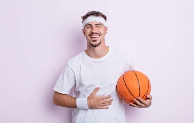 Genç yakışıklı bir adam komik bir şakaya yüksek sesle gülüyor. Basketbol konsepti