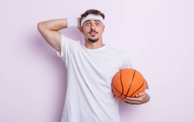 Genç ve yakışıklı bir adam stresli, endişeli ya da korkmuş hissediyor. Elleri başının üstünde. Basketbol konsepti
