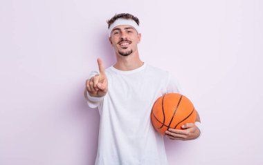 Genç yakışıklı adam gururla gülümsüyor ve kendinden emin bir numara oluyor. Basketbol konsepti
