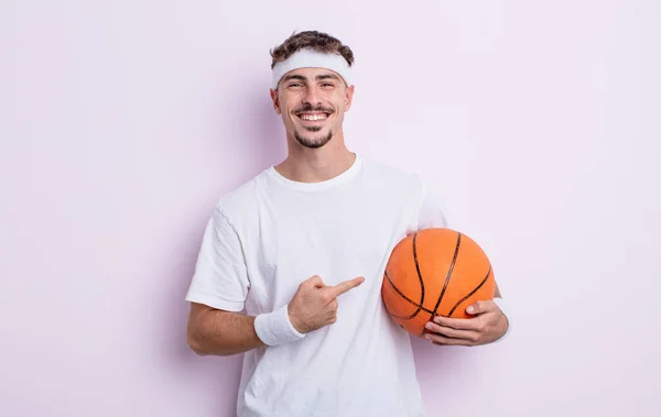年轻英俊的男子兴高采烈地笑了笑 感到快乐 指指点着旁边 篮球概念 — 图库照片