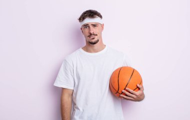 Kafası karışmış ve kafası karışmış genç yakışıklı bir adam. Basketbol konsepti