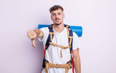 Genç ve yakışıklı bir adam kendini kötü hissediyor, baş parmağını kaldırıyor. Yürüyüş konsepti