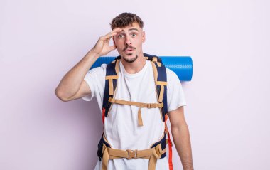 Genç yakışıklı adam mutlu, şaşkın ve şaşırmış görünüyor. Yürüyüş konsepti