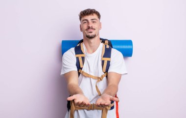 Genç ve yakışıklı bir adam arkadaşça gülümsüyor ve bir konsept sunuyor. Yürüyüş konsepti