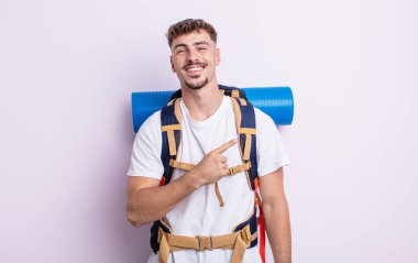 Genç yakışıklı adam neşeyle gülümsüyor, mutlu hissediyor ve bir tarafı işaret ediyor. Yürüyüş konsepti