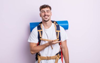 Genç yakışıklı adam neşeyle gülümsüyor, mutlu hissediyor ve bir konsept gösteriyor. Yürüyüş konsepti