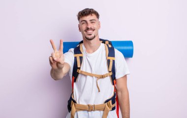 Genç yakışıklı adam gülümsüyor ve arkadaş canlısı görünüyor, iki numarayı gösteriyor. Yürüyüş konsepti