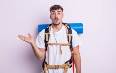 Genç, yakışıklı adam şaşırmış ve şok olmuş görünüyor. Çenesi düşmüş, elinde bir nesne var. Yürüyüş konsepti