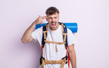 Genç yakışıklı adam mutsuz ve stresli görünüyor, intihar jesti silah işareti yapıyor. Yürüyüş konsepti