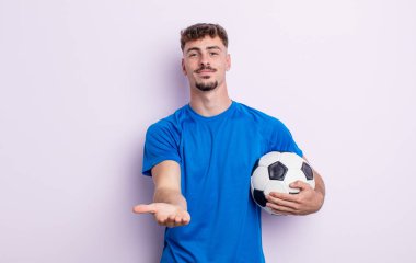 Genç ve yakışıklı bir adam arkadaşça gülümsüyor ve bir konsept sunuyor. futbol kavramı