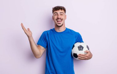 Genç yakışıklı adam kendini mutlu hissediyor ve inanılmaz bir şeye hayret ediyor. futbol kavramı
