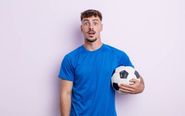 Genç ve yakışıklı bir adam çok şaşırmış ya da şaşkın görünüyor. futbol kavramı